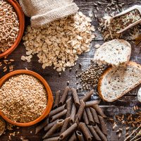 Top view of wholegrain and cereal composition shot on rustic wooden table. This type of food is rich of fiber and is ideal for dieting. The composition includes wholegrain sliced bread, various kinds of wholegrain pasta, wholegrain crackers, grissini, oat flakes, brown rice, spelt and flax seeds. Predominant color is brown. DSRL studio photo taken with Canon EOS 5D Mk II and Canon EF 100mm f/2.8L Macro IS USM